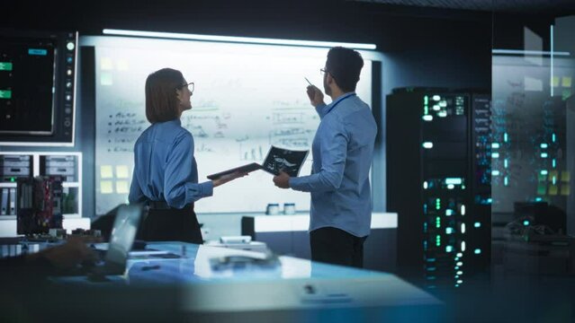 In Technological Research Facility: Portrait of a Team of Two Professional Engineers Using Digital Tablet and White Board to Discuss the Manufacturing Plan for Product Development