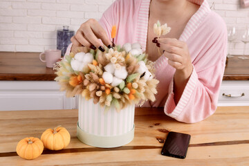 woman in housecoat with bouquet of dried flowers in the kitchen