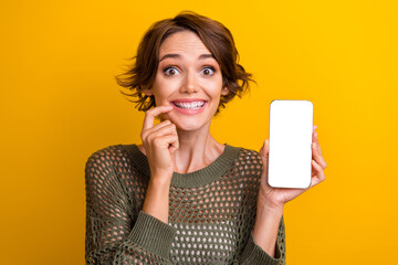 Photo portrait of attractive young woman interested gadget screen dressed stylish knitted khaki clothes isolated on yellow color background