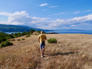 Man hiking on Lin peninsula, Albania, Lake Ohrid in the background. - obrazy, fototapety, plakaty