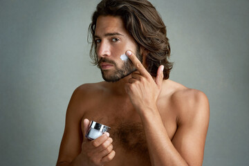 Portrait, beauty or lotion with a shirtless man in studio on a gray background for his grooming...