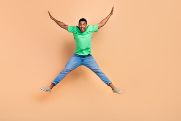 Fototapeta na wymiar Full length photo of crazy funky funny man wear stylish t-shirt jeans flying raising arms up scream isolated on beige color background