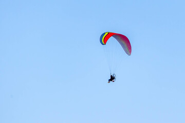 A Powered paragliding also knows as Paramotor flying through the blue sky. Sport. Leisure. Adventure.