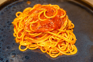 Spaghetti pasta with tomato sauce close up on black plate