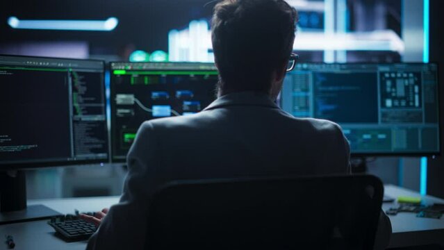 Dynamic, Cinematic Dolly Shot of Male Professional Developer Working in Modern Office: Programmer Using Desktop Computer, Writing Code for an Innovative Technological Internet Product Launch.