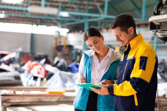 car lift under vehicle. Accident Inspector Inspect damage car caused by car crash on the road with female customer. Car insurance agent examining car by Claim form clipboard in garage. Motor insurance