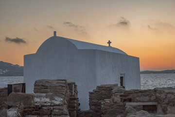 Sunset over ancient whitewashed churches and houses in the waterfront of Chora, Mykonos island,...