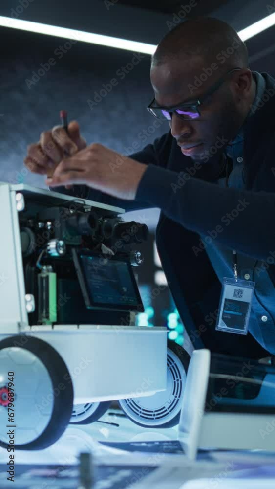 Aufkleber Vertical Screen: Close Up of an Engineer Using a Screwdriver While Developing a Remotely Controlled Delivery Robot. Black Specialist Working in High Tech Research Laboratory with Modern Equipment