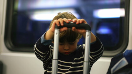 Solo Child Distracting Himself with Suitcase on Train Ride, Little Boy Playing with Handle while...