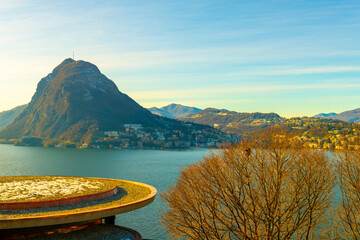 Modern Roof Top and Bare Tree on Lake Lugano and City with Mountain and Blue Sky in Lugano, Ticino...