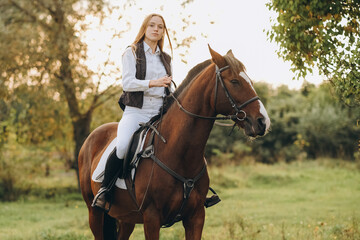 A young female jockey is sitting on her horse in show jumping training. Preparing for the...