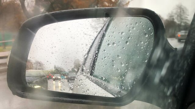 raindrops in the rear view mirror of a car, autumn wet weather, road