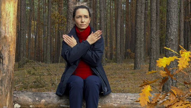 Female tapping her shoulders, crossing hands. Butterfly hug. Woman sitting on a log in the forest.