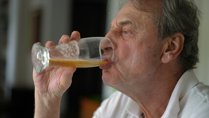 Senior man taking a sip of beer, profile close-up face of older person snacking and drinking...