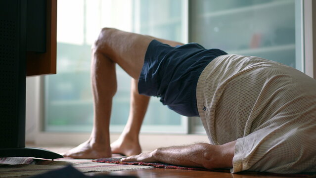 Senior man taking care of his lower back in morning exercise routine to relieve back pain. Elderly caucasian 70s person doing bridge position, spine health in old age