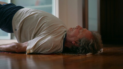 Senior man taking care of his lower back in morning exercise routine to relieve back pain. Elderly...