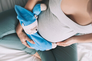 Closeup woman pregnant belly with teddy toy. Concept of pregnancy, maternity, prepare for baby.
