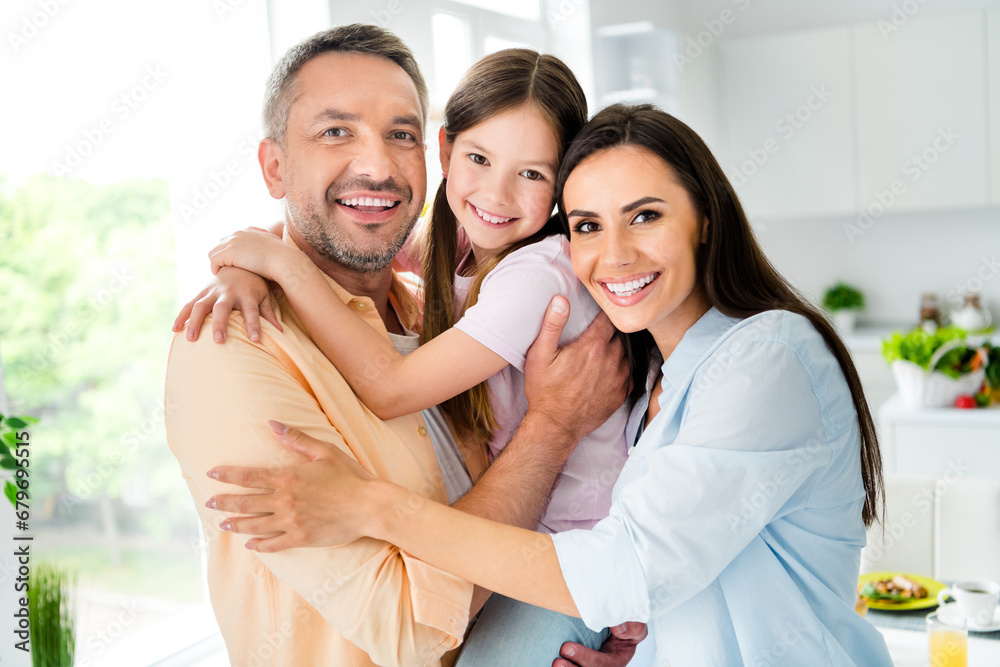 Sticker photo of adorable cheerful dad mom small daughter hugging enjoying weekend time together indoors hom