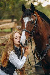 Obraz premium A young female equestrian stands near her horse and prepares for a competition.