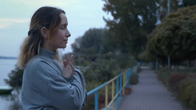 Female tapping her shoulders outdoors near water. Crossing hands. Butterfly hug. EMDR therapy technique.