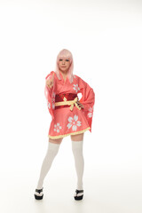 full length of woman in blonde wig and pink kimono pointing at camera on white, cosplay culture