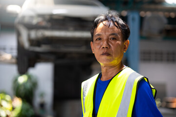 Portrait senior Asian thai male professional mechanic repairs car working in garage. Car...