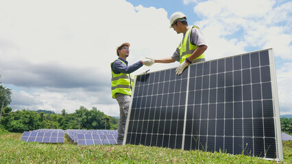 Two asian engineers shaking hands after  installing solar panels . Solar energy clean and green...