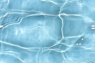 Obraz premium Defocus blurred transparent blue colored clear calm water surface texture with splashes reflection. Trendy abstract nature background. Water waves in sunlight with copy space. Blue watercolor shine.