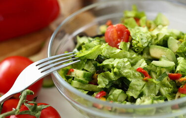 Healthy Chopped Dieting Vegetable Salad Photo. Dish with Organic Cutting Lettuce, Tomato and Cucumber Ingredient in Glass Bowl. Stainless Fork.Home Culinary Food Recipe Partial View Photography