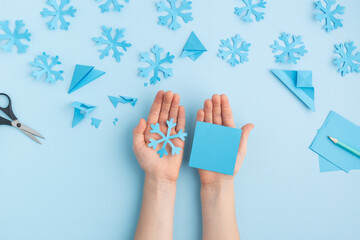 Hands making paper snowflakes on blue child hands