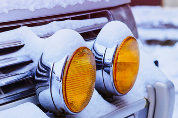 Snowy yellow fog lights of a car in snowy winter. The morning after the snowfall. No people. Close...