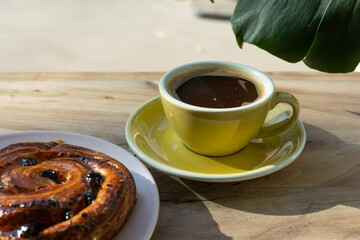 A cup of coffee and a bun on the table