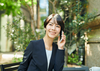 テラス席で電話をする30代女性会社員