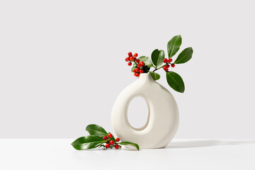  Christmas holly with red berries in white vase. Winter natural decoration