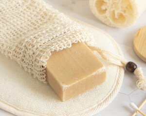 Beige handmade soap bar in soap saver bag near natural sponge close up - obrazy, fototapety, plakaty