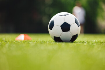 Soccer Ball and Red Cone Marker on Training Pitch. Football Turf. Soccer Stadium in Blurred...