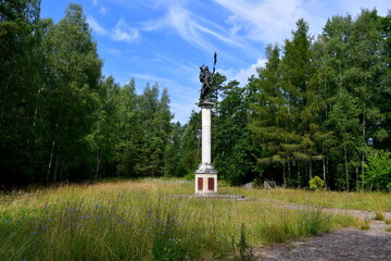 A view of a religious statue or monument on a high pillar standing in the middle of a vast field or...