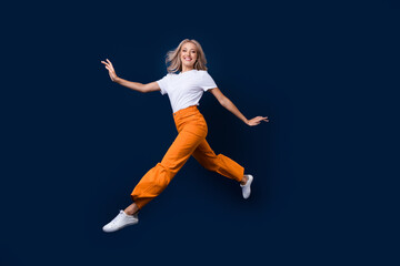 Fototapeta na wymiar Full length photo of adorable pretty girl jumping going moving empty space isolated on dark blue color background