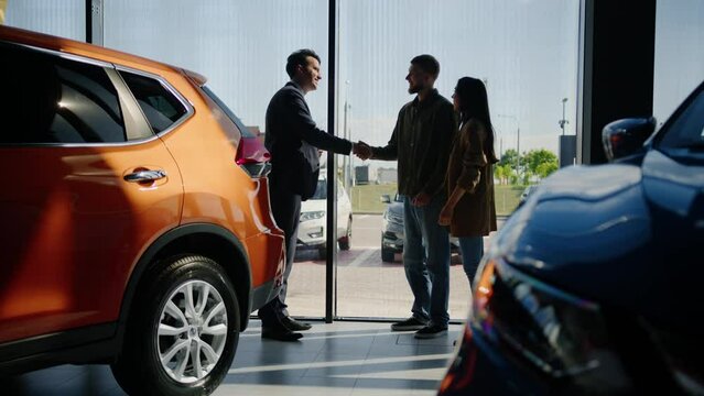 The customer service manager hands over the keys to the new family car to the man. Happy family during the purchase