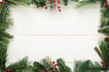 A pine garland border on a white wood background. 