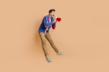 Full length photo of overjoyed energetic funky businessman jumping hold loudspeaker toa empty space...