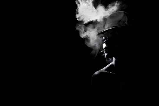 Sexy portrait of a smoking woman wearing a hat, backlit silhouette, black and white film noir style with copy space
