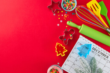 Getting ready to bake holiday desserts. Top view shot of calendar, candies, frost-kissed fir branch, pastry tools, baking molds, stars on red background with advert placement