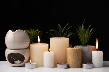 Burning candles and an aroma lamp on a black background. Incense, background for meditation and...