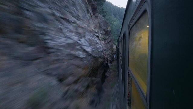 Passenger train rides by rail in a beautiful mountain fores at dawn