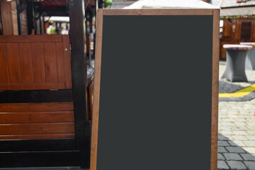 Wooden rustic blackboard in front of restaurant entrance. Mock up menu blank blackboard sign stand...