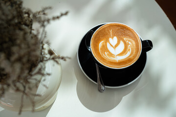 Hot coffee latte with latte art milk foam in cup mug on wood desk on top view. As breakfast In a coffee shop at the cafe,during business work concept,vintage style