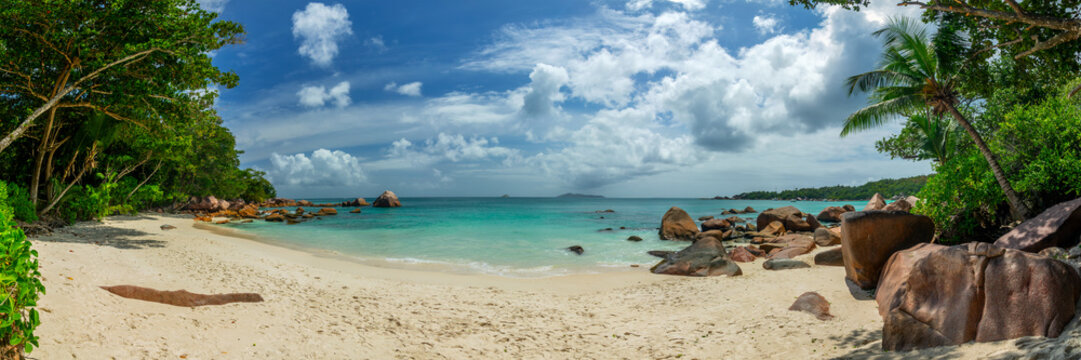 Panorama with palm trees and granite rocks at Anse Lazio, scenic beach in Praslin island, Seychelles web banner