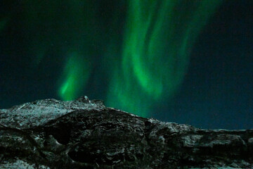 Bright Green Colours of the Northern Light, Aurora Borealis illuminate the Night Sky over the beach...