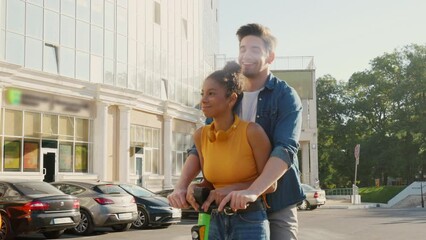 Two friends having fun riding shared electric push scooters in the city.